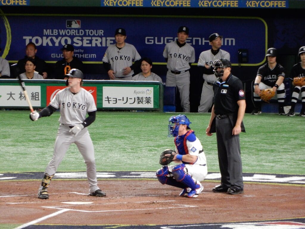 A Dodgers catcher crouching behind home plate as a Yomiuri Giants batter waits at the Tokyo Dome.