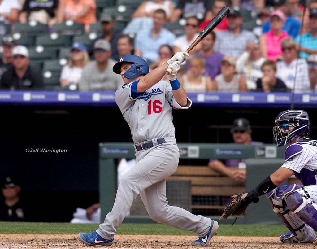 Will Smith in a gray Dodgers uniform finishing a home run swing as the Rockies catcher looks on.